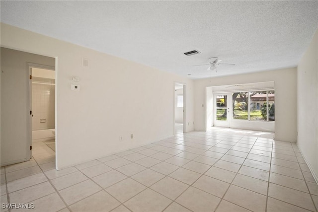 spare room featuring ceiling fan, light tile patterned floors, and a textured ceiling