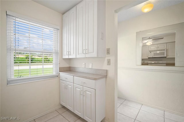 kitchen featuring white cabinetry, plenty of natural light, light tile patterned floors, and range