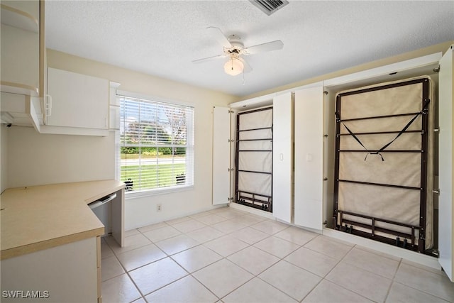 interior space featuring a textured ceiling, ceiling fan, and light tile patterned flooring