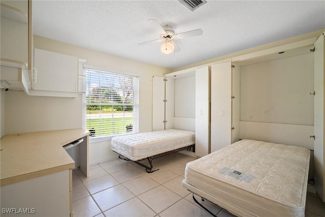 tiled bedroom featuring a textured ceiling and ceiling fan