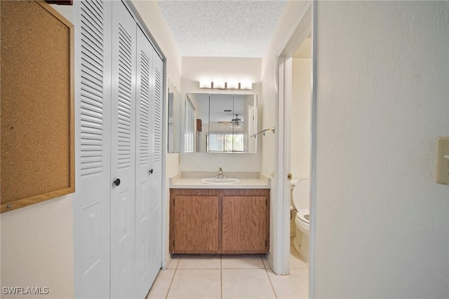 bathroom featuring tile patterned floors, vanity, a textured ceiling, ceiling fan, and toilet