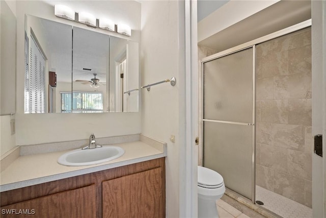 bathroom featuring vanity, ceiling fan, toilet, and a shower with door