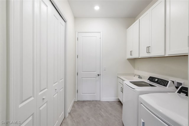 washroom with sink, independent washer and dryer, and cabinets