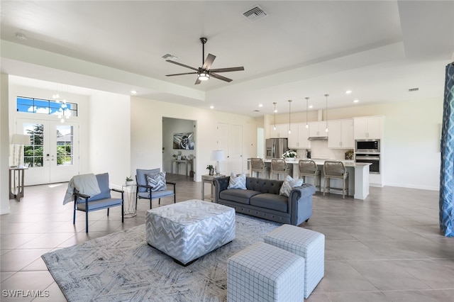 tiled living room featuring french doors and ceiling fan with notable chandelier