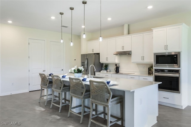 kitchen featuring sink, an island with sink, hanging light fixtures, stainless steel appliances, and white cabinets