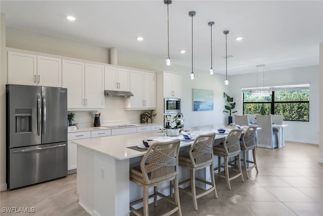 kitchen featuring appliances with stainless steel finishes, white cabinets, a kitchen island with sink, and hanging light fixtures