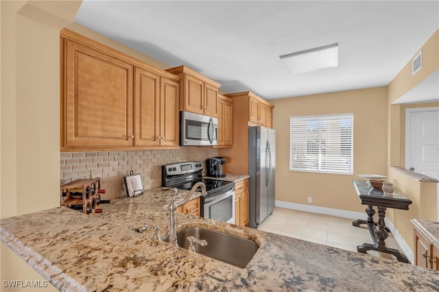 kitchen with light stone countertops, stainless steel appliances, backsplash, kitchen peninsula, and light tile patterned floors