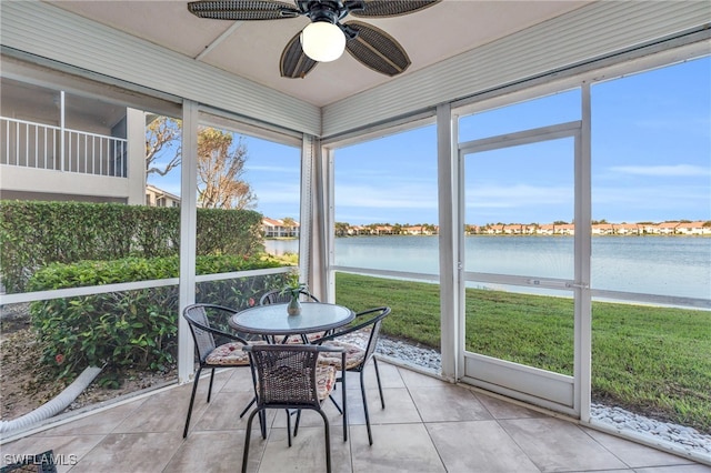 sunroom with ceiling fan and a water view