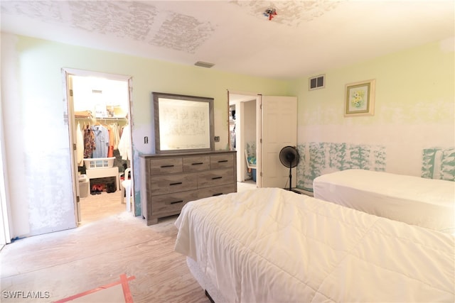 bedroom with a spacious closet, a closet, and light wood-type flooring