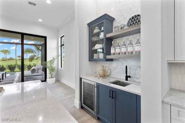 bar featuring crown molding, sink, wine cooler, light stone countertops, and blue cabinetry