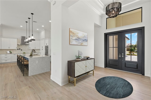 foyer entrance featuring french doors, light wood-type flooring, crown molding, and sink