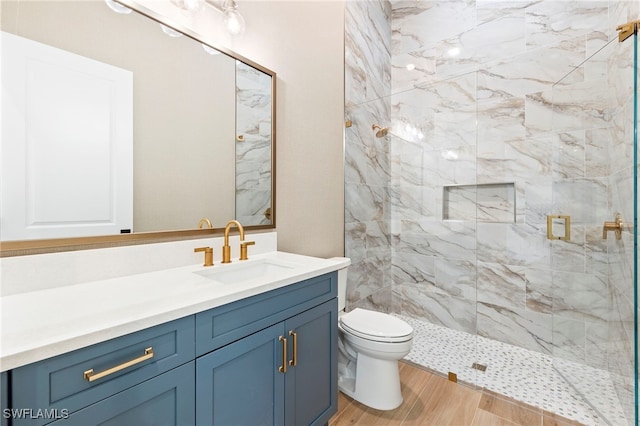 bathroom featuring hardwood / wood-style floors, vanity, toilet, and a tile shower