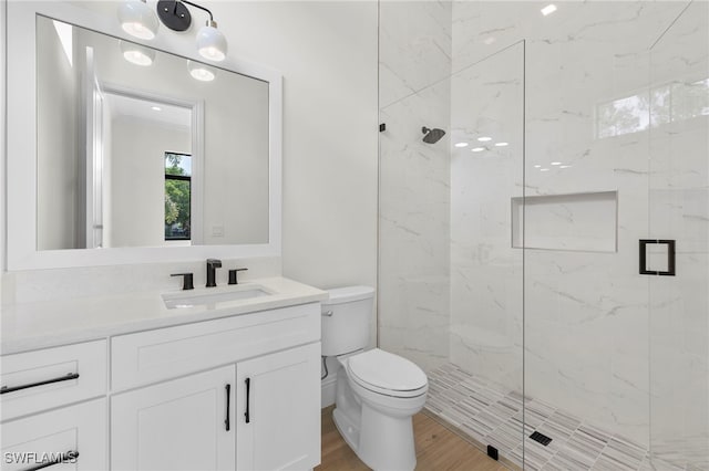 bathroom with hardwood / wood-style floors, vanity, a shower with shower door, and toilet