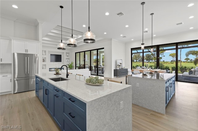 kitchen featuring white cabinets, sink, blue cabinetry, a large island, and stainless steel refrigerator