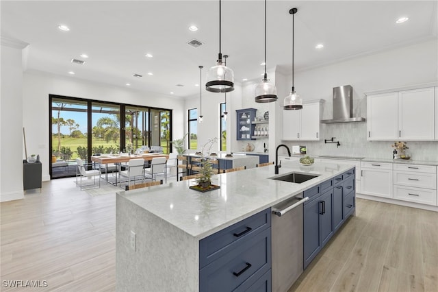 kitchen with white cabinets, sink, stainless steel dishwasher, and wall chimney range hood