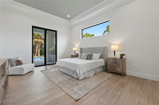 bedroom with light wood-type flooring, access to outside, multiple windows, and a tray ceiling