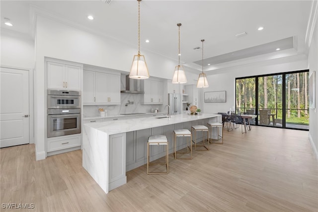 kitchen with double oven, light hardwood / wood-style flooring, a spacious island, and decorative light fixtures