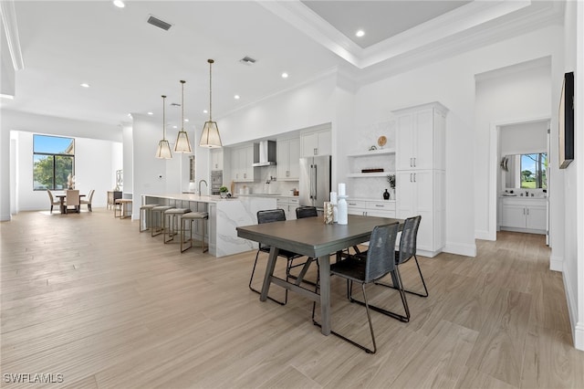 dining area with light hardwood / wood-style flooring, ornamental molding, and sink