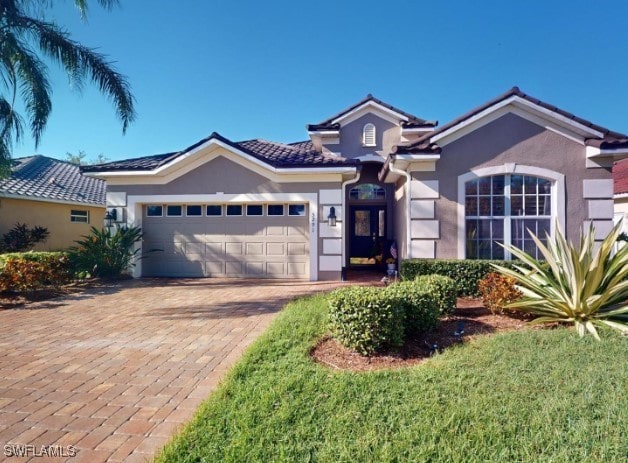 5291 Laurel Oak Ct, North Port, FL 34287 - view of front facade featuring an attached garage, decorative driveway, stucco siding, and a tiled roof