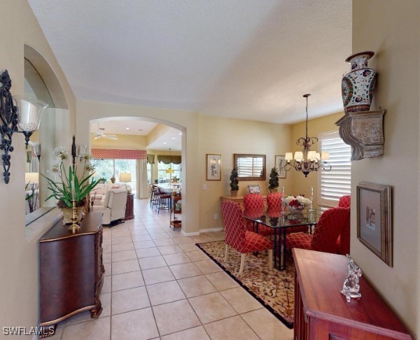 5291 Laurel Oak Ct, North Port, FL 34287 - dining area featuring arched walkways, baseboards, a notable chandelier, and light tile patterned floors