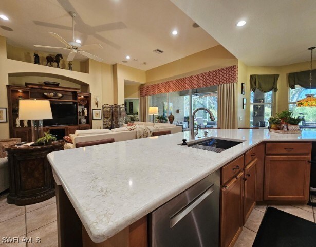 kitchen with a center island with sink, sink, light tile patterned flooring, stainless steel dishwasher, and ceiling fan