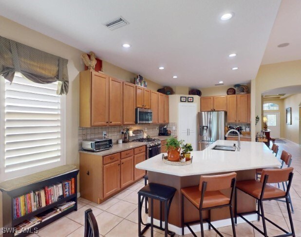 5291 Laurel Oak Ct, North Port, FL 34287 - kitchen featuring a breakfast bar area, visible vents, appliances with stainless steel finishes, arched walkways, and a sink