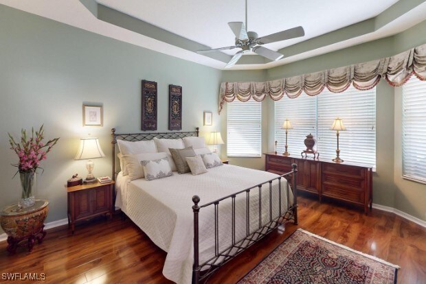 5291 Laurel Oak Ct, North Port, FL 34287 - bedroom featuring a raised ceiling, baseboards, and wood finished floors