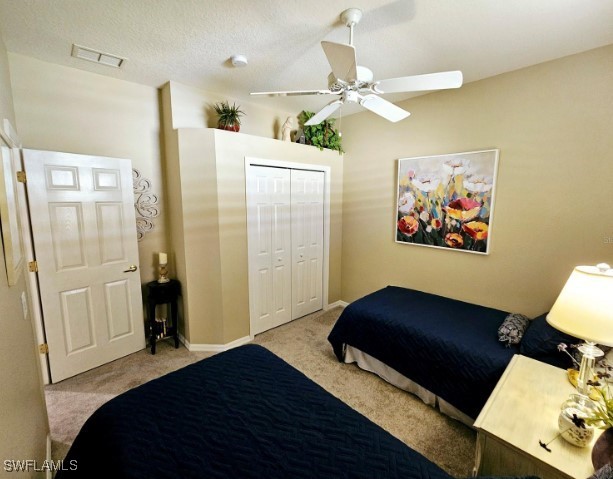 carpeted bedroom featuring a textured ceiling, a closet, and ceiling fan