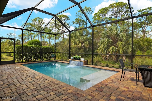 view of pool with pool water feature, a patio area, and glass enclosure