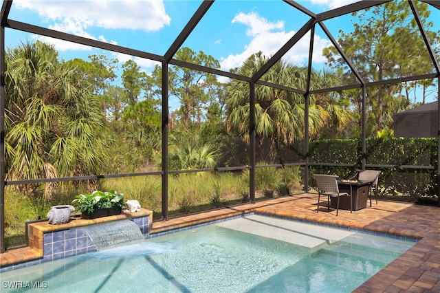 view of pool with pool water feature, glass enclosure, and a patio area