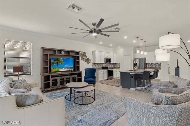 living room with light tile patterned floors, crown molding, and ceiling fan