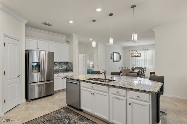 kitchen with sink, white cabinetry, stainless steel appliances, ornamental molding, and a center island with sink