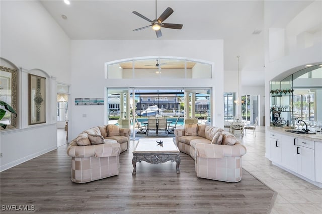 1524 SW 56th Ter, Cape Coral, FL 33914 - living room featuring light wood-style floors, ceiling fan, a high ceiling, and a healthy amount of sunlight