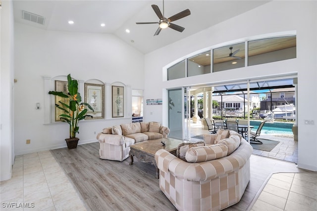 living room with ceiling fan, high vaulted ceiling, and light hardwood / wood-style floors