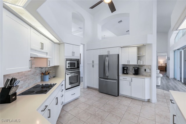 kitchen featuring appliances with stainless steel finishes, white cabinetry, high vaulted ceiling, and backsplash