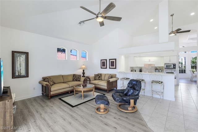 living room featuring ceiling fan, high vaulted ceiling, and light hardwood / wood-style floors