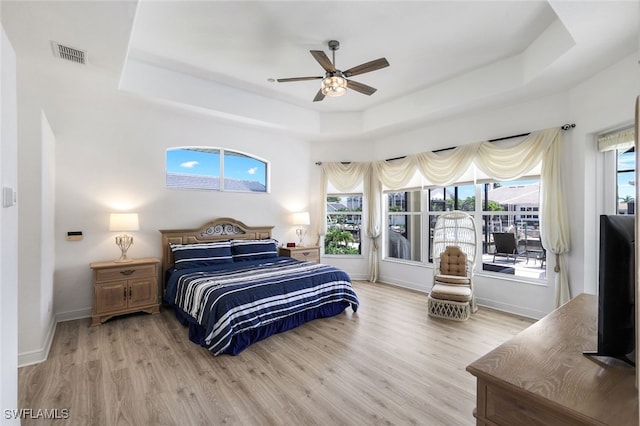 bedroom featuring ceiling fan, a raised ceiling, and light hardwood / wood-style floors