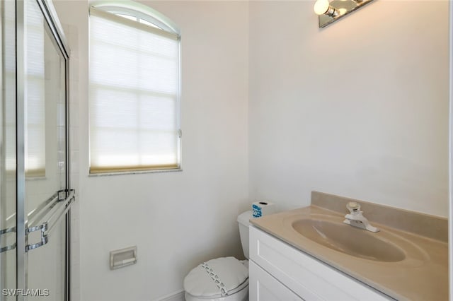 bathroom with vanity, a shower with shower door, and toilet