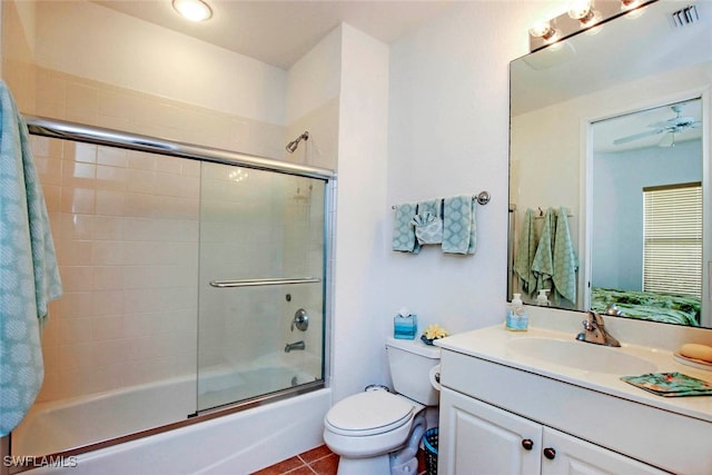 full bathroom with vanity, combined bath / shower with glass door, tile patterned flooring, ceiling fan, and toilet