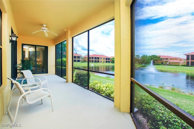 sunroom with ceiling fan and a water view