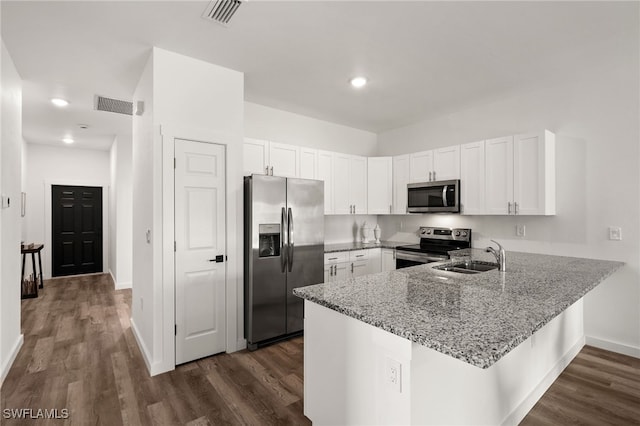 kitchen with kitchen peninsula, appliances with stainless steel finishes, and white cabinetry