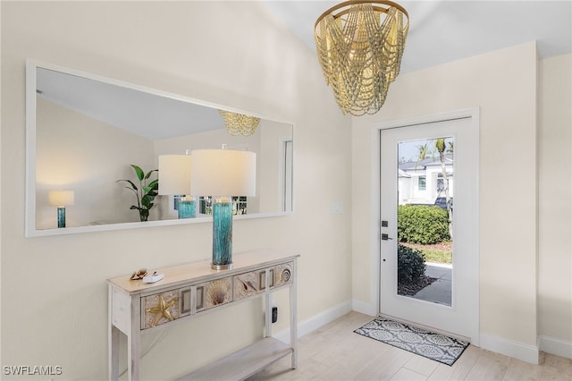 foyer with a notable chandelier, lofted ceiling, and light wood-type flooring