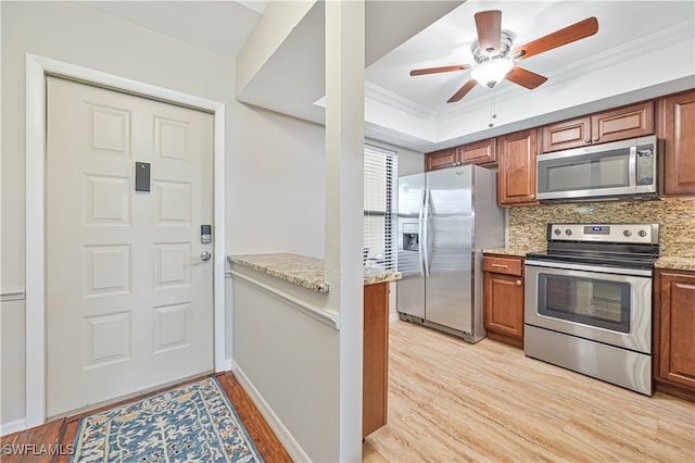 kitchen featuring light stone countertops, light wood-type flooring, ornamental molding, stainless steel appliances, and decorative backsplash