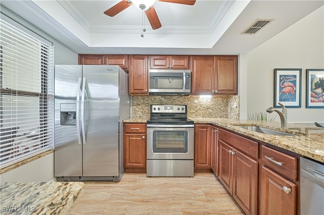 kitchen featuring light stone countertops, sink, appliances with stainless steel finishes, and a raised ceiling