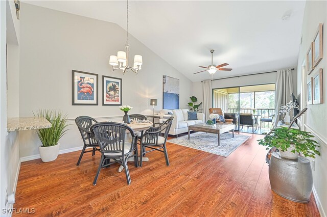 dining area with hardwood / wood-style floors, high vaulted ceiling, and ceiling fan with notable chandelier