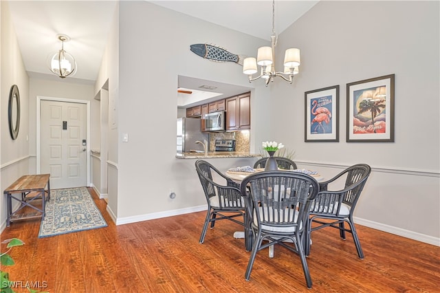 dining space with an inviting chandelier, hardwood / wood-style floors, and vaulted ceiling