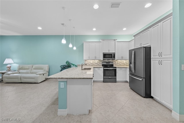 kitchen featuring appliances with stainless steel finishes, sink, backsplash, white cabinetry, and decorative light fixtures