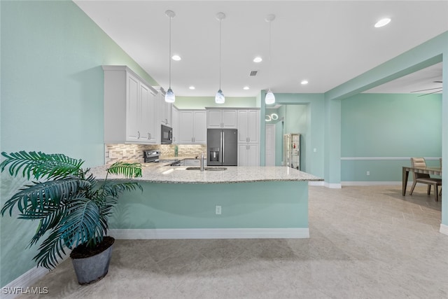 kitchen featuring kitchen peninsula, stainless steel appliances, decorative light fixtures, white cabinetry, and tasteful backsplash