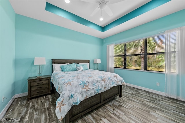 bedroom featuring hardwood / wood-style floors, a raised ceiling, and ceiling fan