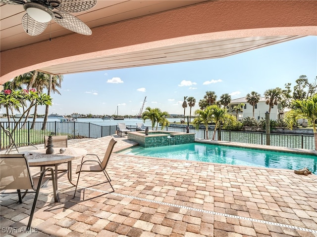 view of pool featuring an in ground hot tub, a water view, ceiling fan, and a patio area